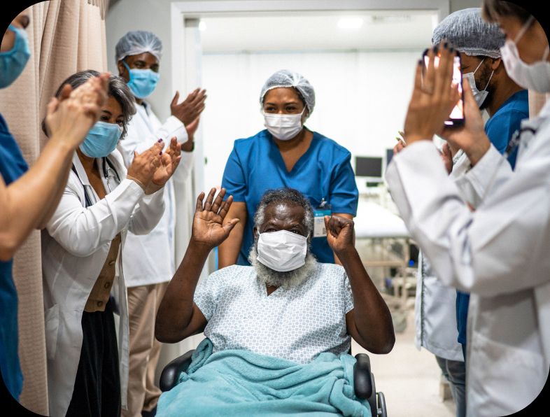 Patient in a wheelchair celebrating with full medical team.