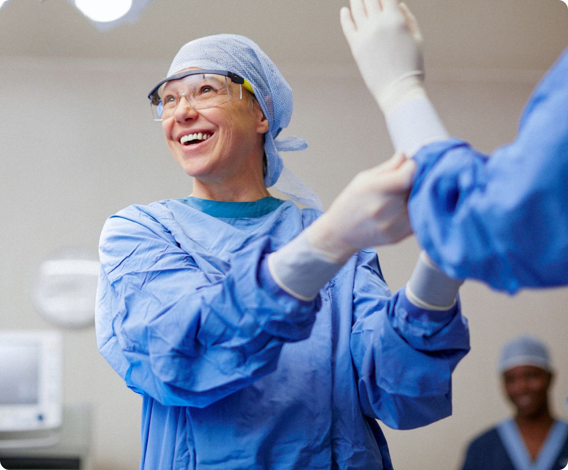 Surgeon helping colleague scrub in to operating room.